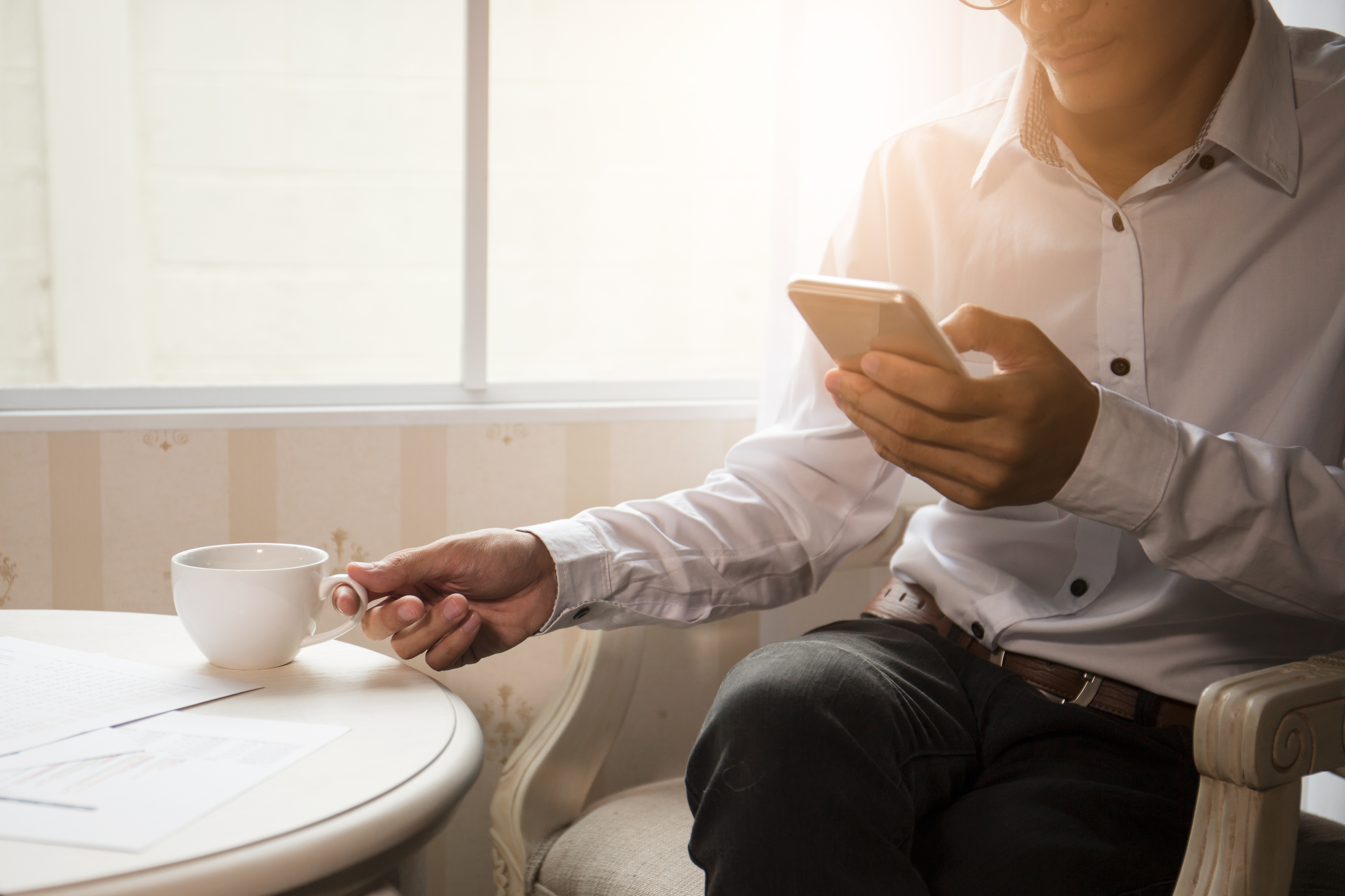 Business man sitting and having coffee while on the phone.